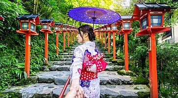 woman wearing japanese traditional kimono holding man's hand and leading him to Kifune shrine, Kyoto in Japan.